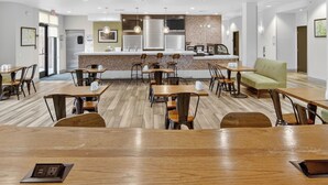 A modern hotel lobby with wooden flooring, a central bar area, and seating arrangements. - Holiday Inn & Suites Dallas-Addison by IHG (Addison)