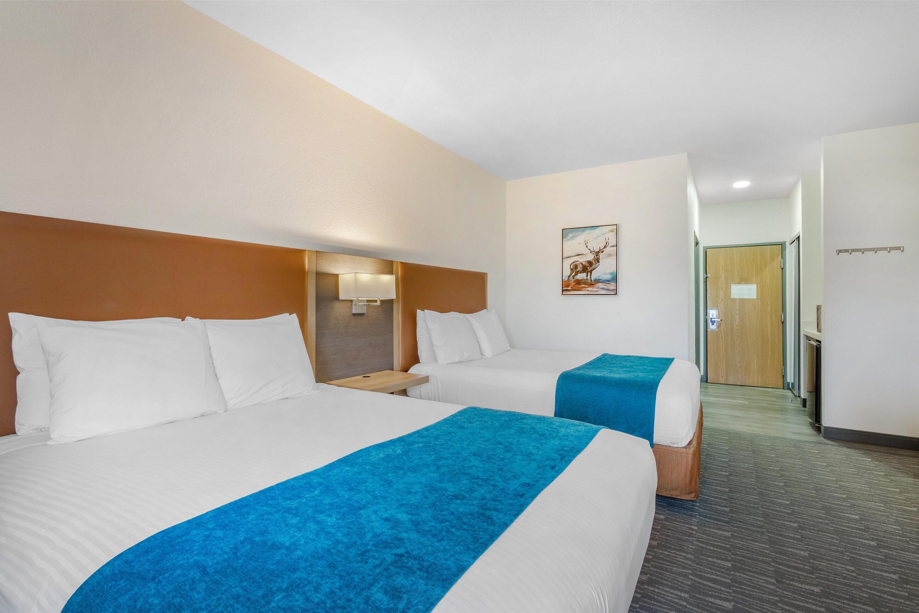 Une chambre d’hôtel avec deux lits, une table de chevet, une lampe et un tableau au mur.