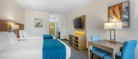 Habitació d'hotel amb dos llits, un escriptori amb una cadira, un televisor penjat a la paret i un quadre.