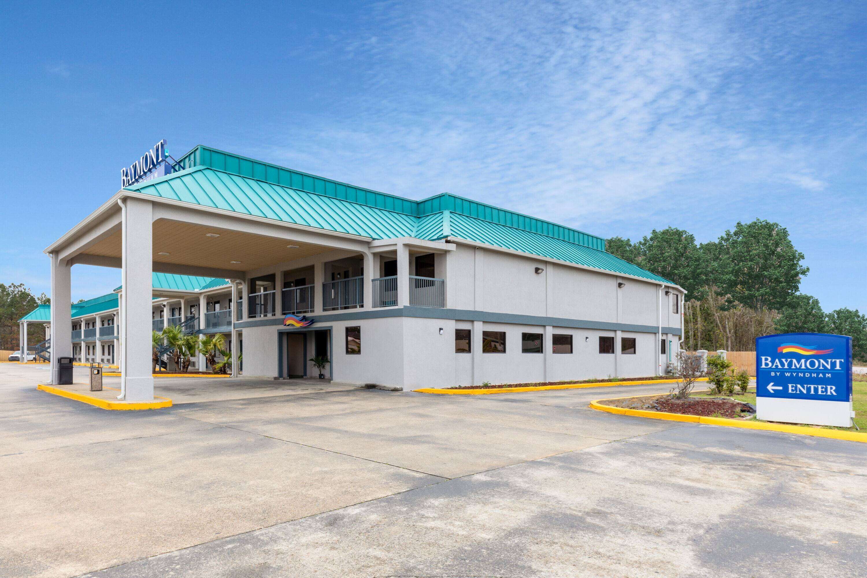 A Baymont by Wyndham hotel with a covered entrance, a sign indicating the entrance, and a parking lot.