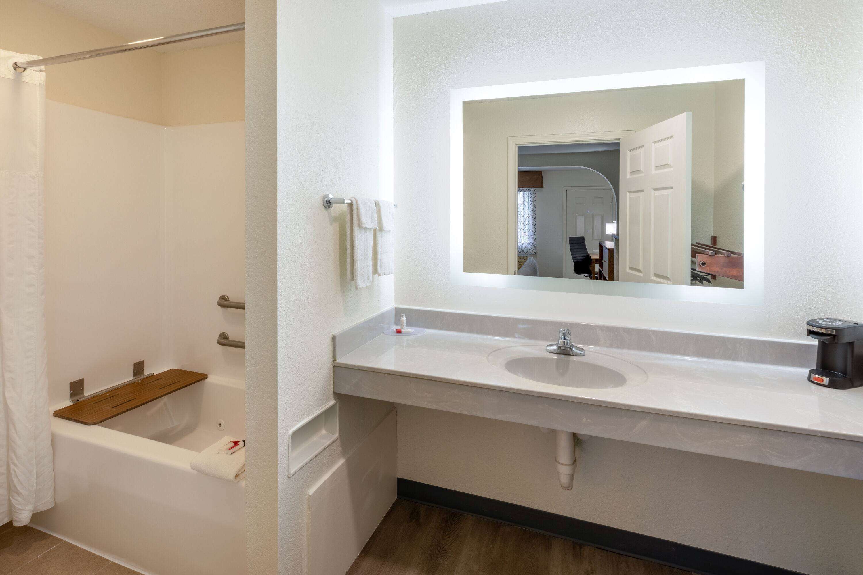 Ein Badezimmer mit einer Badewanne, einem Waschbecken, einem Spiegel und einer Duschvorhang.