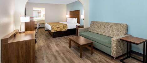A hotel room with a bed, a sofa, a desk, and a mirror.