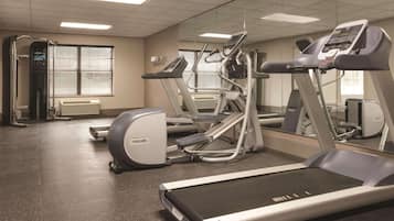 Un gimnasio con cintas de correr, elípticas y un espejo grande.