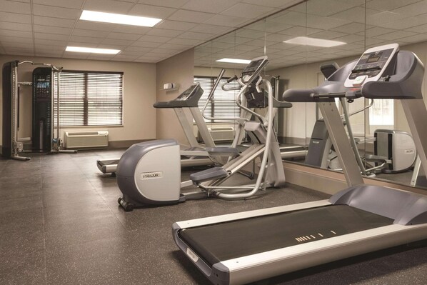 A gym with treadmills, ellipticals, and a mirrored wall.