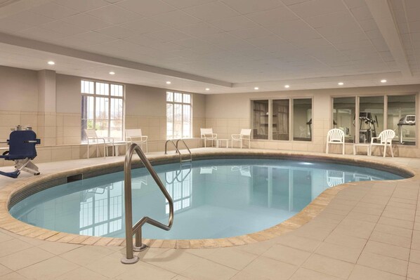 An indoor swimming pool with clear water, surrounded by tiled walls and windows.