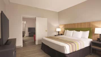 A hotel room with a large bed, a TV, a desk, and a chair.