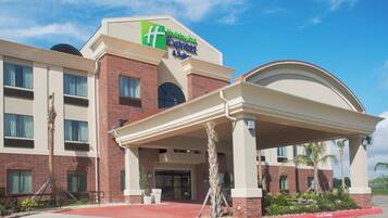 A Holiday Inn Express & Suites hotel with a brick facade, a covered entrance, and a red curb indicating no parking.