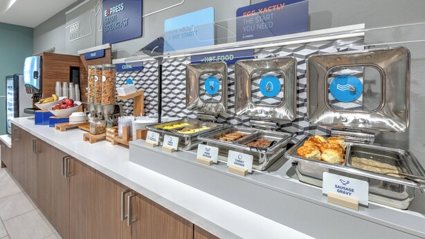 A buffet with labeled food sections including sausage, eggs, and fruit. - Holiday Inn Express Hotel & Suites Winnie by IHG (Winnie)