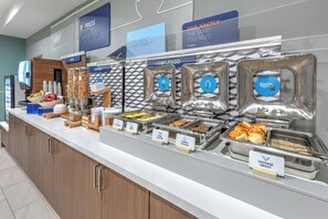 A buffet with labeled food sections including sausage, eggs, and fruit. - Holiday Inn Express Hotel & Suites Winnie by IHG (Winnie)