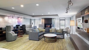 A modern living room with a sectional sofa, armchairs, a coffee table, and a fireplace. - Courtyard by Marriott Princeton (Princeton)