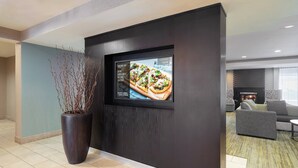 A modern lobby with a large TV screen, a potted plant, and a seating area with a fireplace. - Courtyard by Marriott Princeton (Princeton)