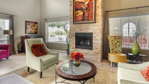 A spacious living room with a fireplace, comfortable seating, and large windows offering views of the outdoors. - Best Western Plus Winslow Inn (Winslow)