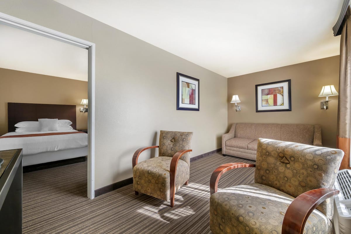 A hotel room with a bed, two armchairs, a sofa, and two wall-mounted lamps.