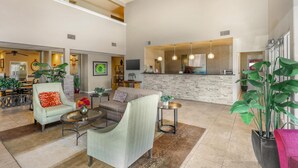 A spacious living area with a high ceiling, a kitchen with a stone backsplash, and a dining area with a ceiling fan. - Best Western Plus Winslow Inn (Winslow)