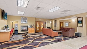 A hotel lobby with a reception desk, seating area, and a fireplace.