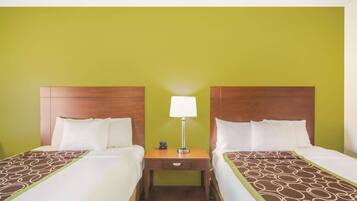 A hotel room with two beds, a nightstand with a lamp, and a green wall.