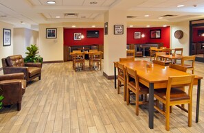 Ein geräumiger Essbereich mit Holztischen und -stühlen, einer roten Akzentwand und einer Sitzecke mit Ledersofas.