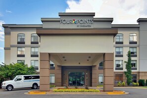 Eingang eines Four Points by Sheraton Hotels, vor dem ein Lieferwagen geparkt ist.