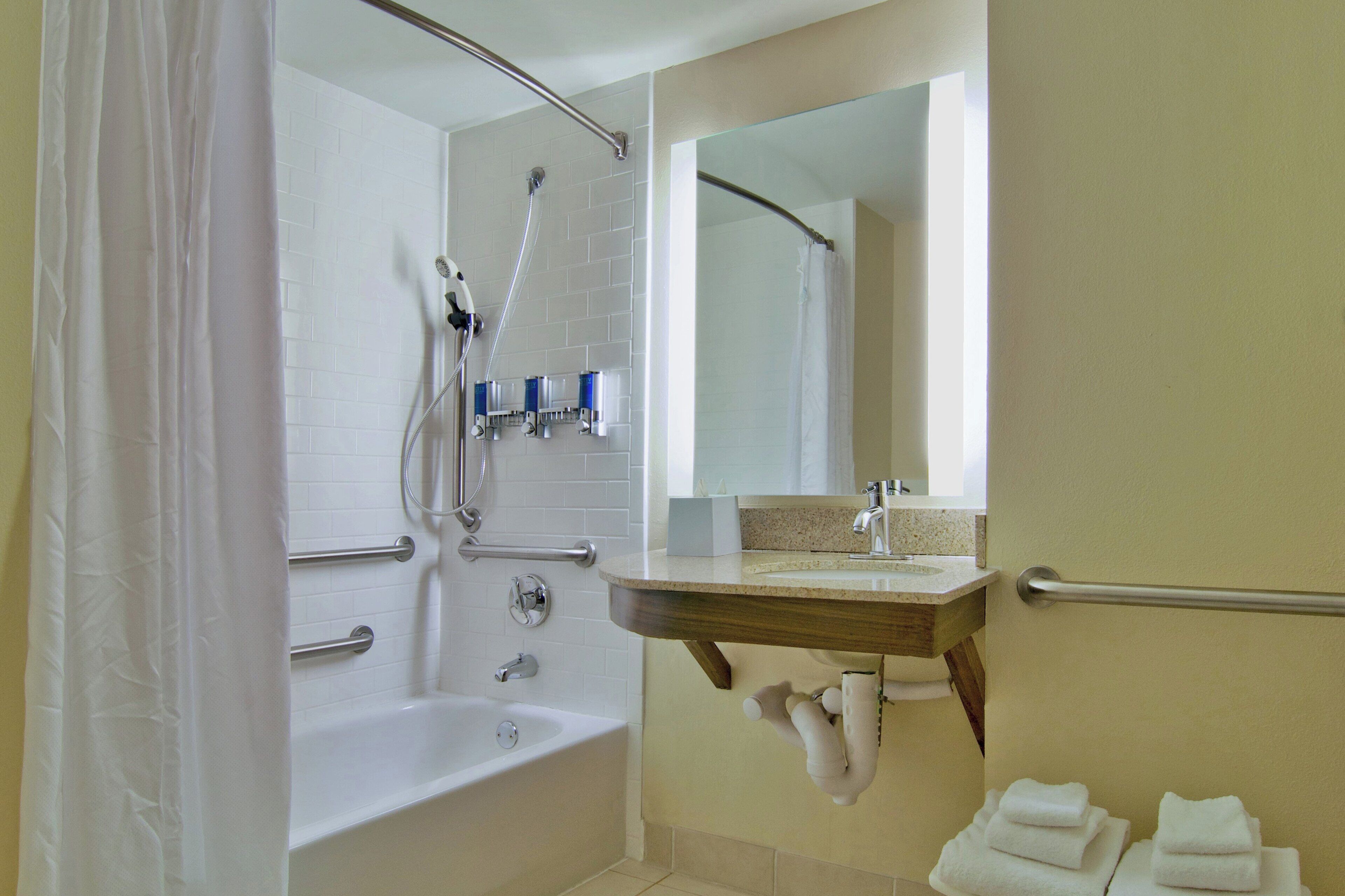 A bathroom with a bathtub, a shower, a vanity with a mirror, and a towel rack.
