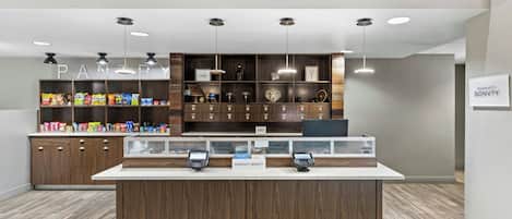 A clean, modern pantry area with a variety of snacks and a self-service checkout counter.