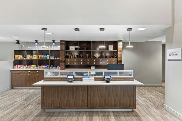 A clean, modern pantry area with a variety of snacks and a self-service checkout counter.