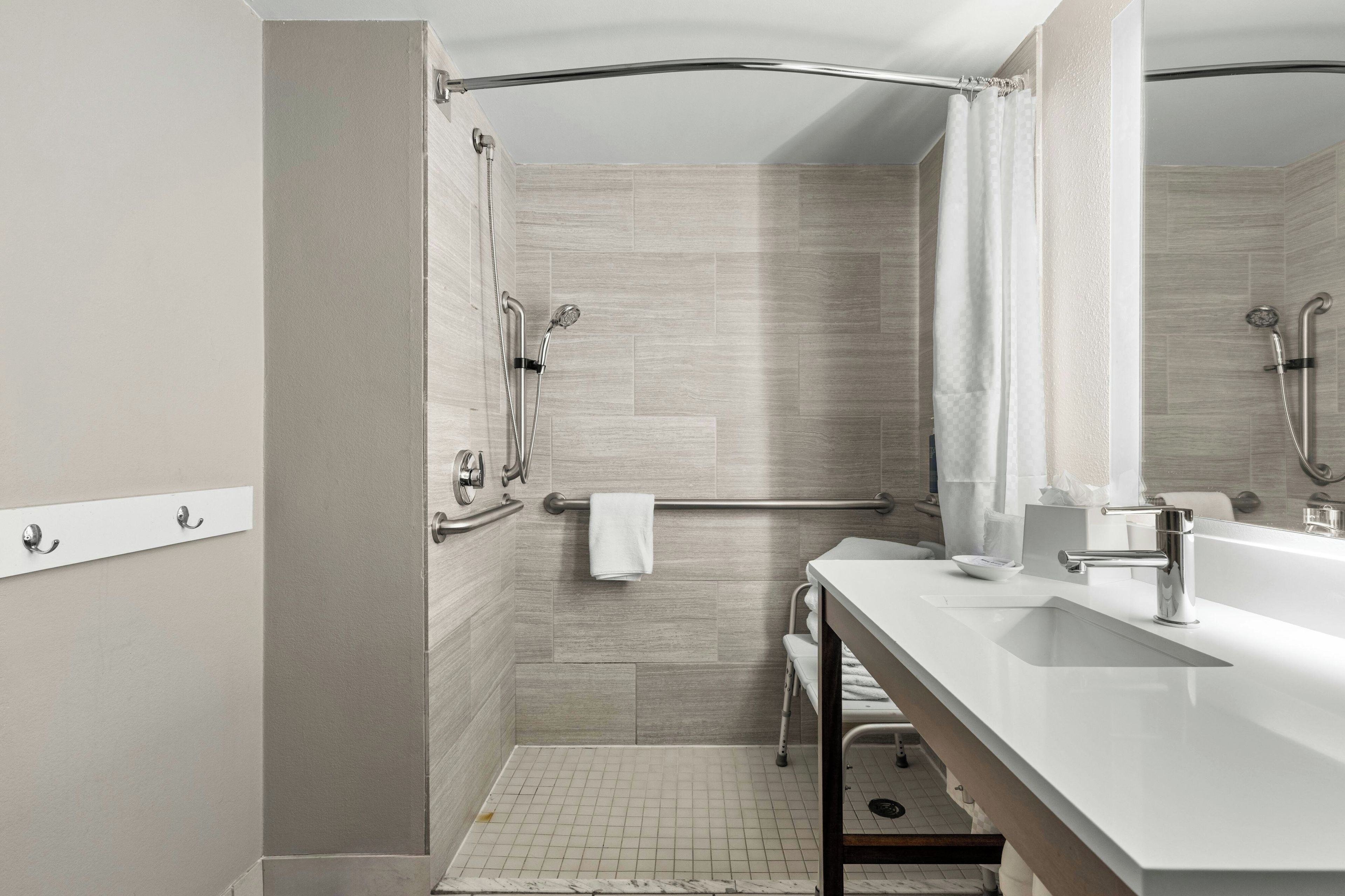 A modern bathroom with a shower, a sink, and a mirror.