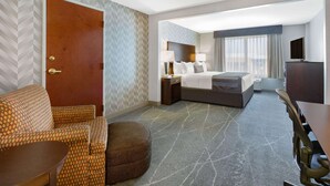 A hotel room with a bed, a desk, a chair, a sofa, and a television. - Wingate by Wyndham Tinley Park (Tinley Park)