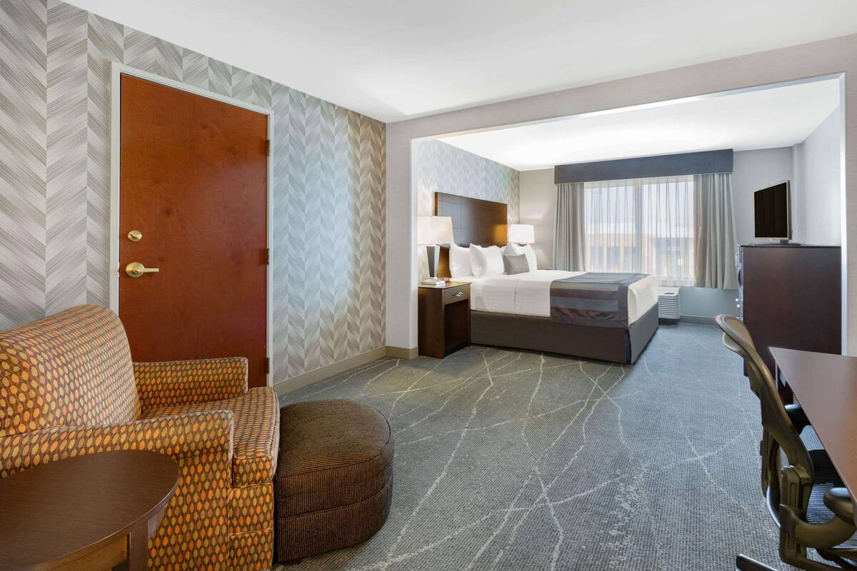 Ein Hotelzimmer mit Bett, Schreibtisch, Stuhl, Sofa und Fernseher.