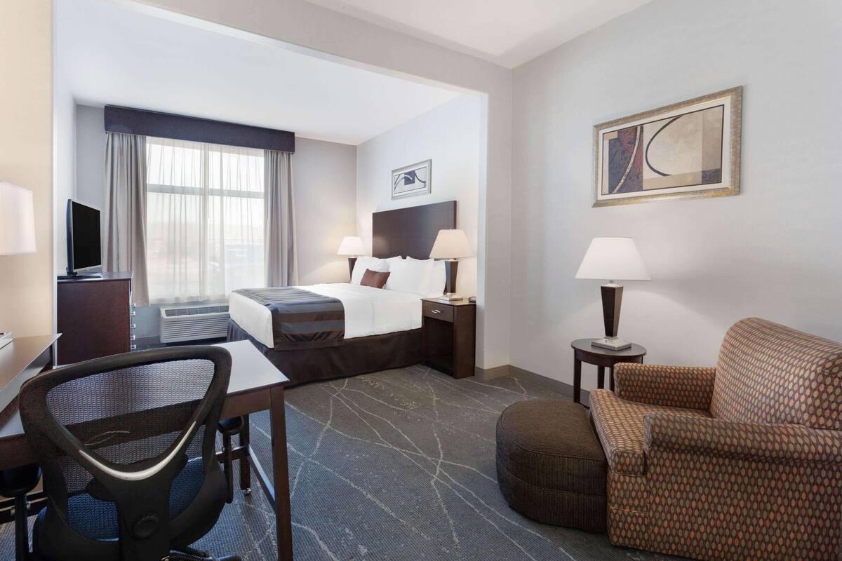 Ein Hotelzimmer mit Bett, Schreibtisch, Stuhl und einer Couch.