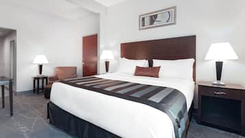 Une chambre d’hôtel avec un grand lit, deux tables de chevet avec des lampes, une chaise et une porte.
