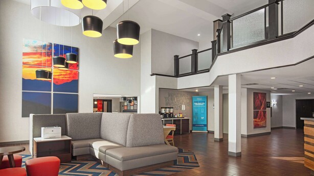 Un moderno vestíbulo de hotel con una zona de estar, una escalera y una recepción.