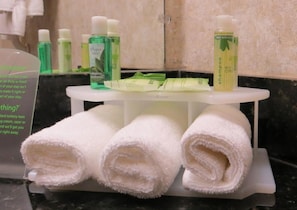 A bathroom with toiletries including a bottle of shampoo, a bottle of mouthwash, and a bottle of lotion. There are three rolled towels on a tray. - Holiday Inn Express Temecula by IHG (Temecula)