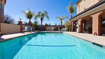 Una piscina al aire libre, sillones reclinables de piscina