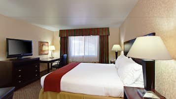 A hotel room with a bed, a desk, a television, and a window with curtains.