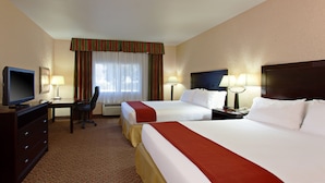 A hotel room with two beds, a desk with a television, and two lamps.