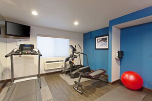 A fitness room with exercise equipment, a treadmill, a stationary bike, and a red exercise ball.