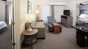 Habitación de hotel con cama, sofá, escritorio, silla, televisor y lámpara.
