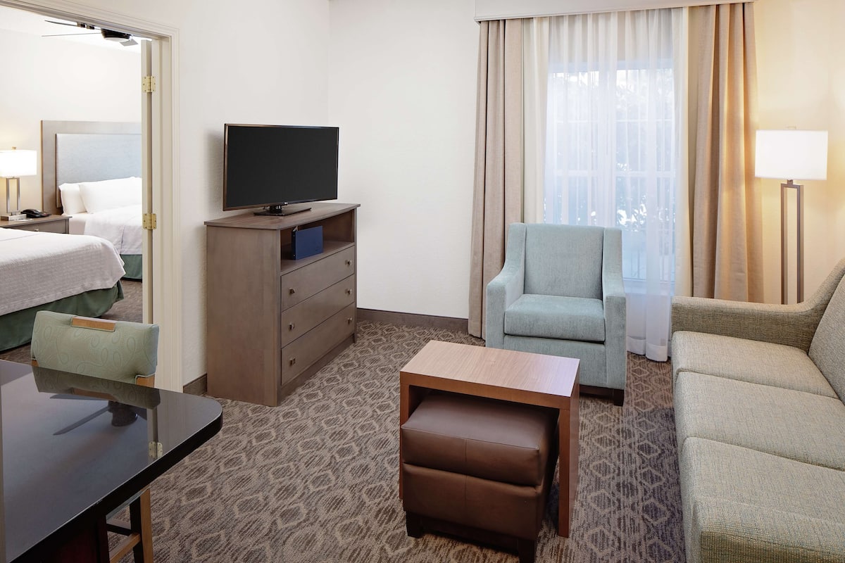Habitación de hotel con cama, televisión, escritorio, silla y sofá.