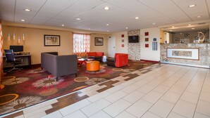 A hotel lobby with a reception desk, seating area with sofas and chairs, a television, and a patterned carpet. - Best Western Of Clewiston (Clewiston)