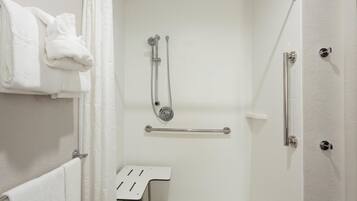 A shower area with a grab bar, a towel rack, and a small table.