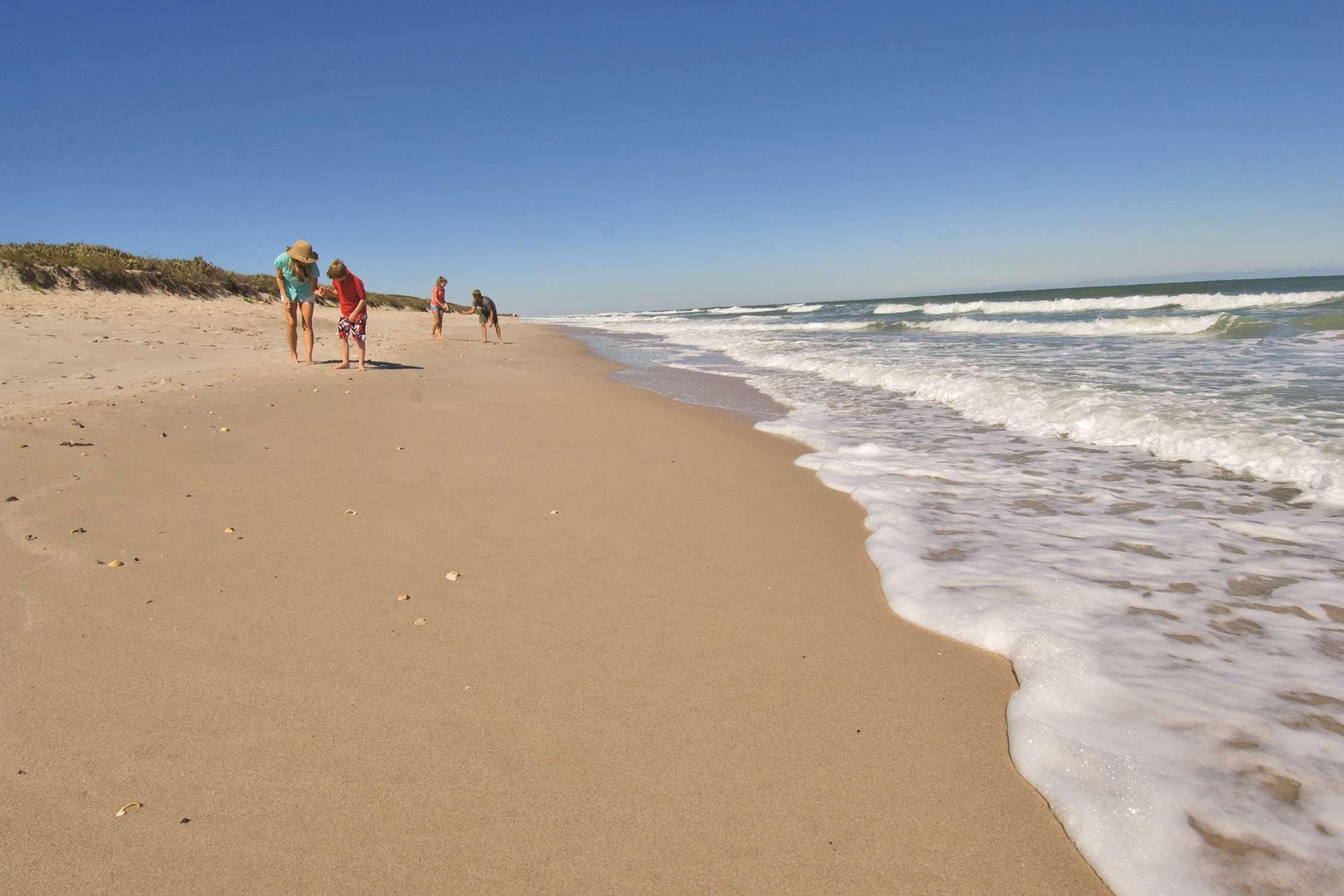 A sandy beach with gentle waves and a clear sky.