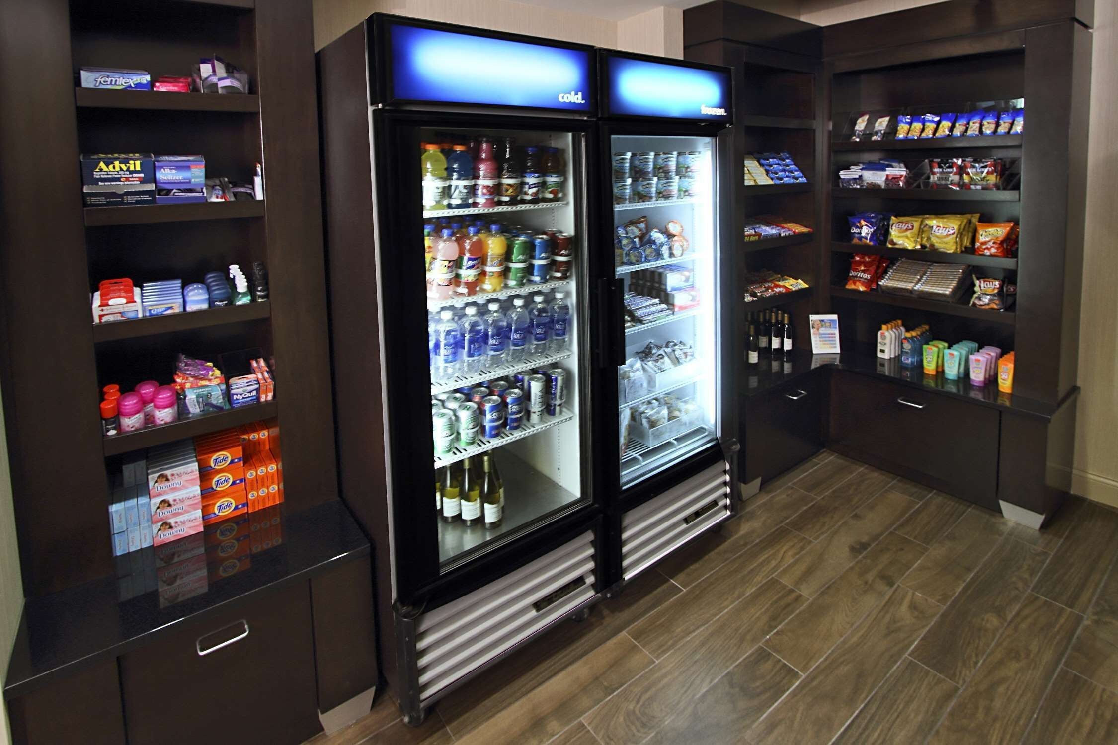 A vending area with two refrigerated beverage dispensers and shelves stocked with snacks and drinks.