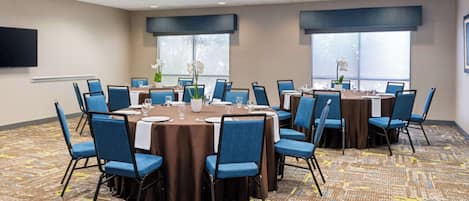 A conference room with round tables, blue chairs, and a patterned carpet.