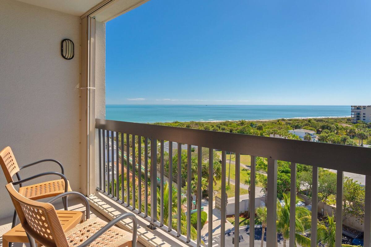A balcony with a view of the ocean, a chair, and a railing.
