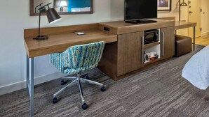 A hotel room with a wooden desk, a chair, a television, a microwave, and a small cabinet. - Hampton Inn Orlando-Maingate South (Davenport)