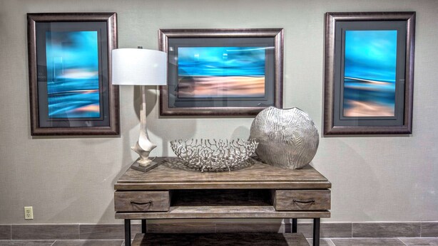 A desk with a lamp, decorative bowl, and framed artwork on the wall. - Hampton Inn Orlando-Maingate South (Davenport)