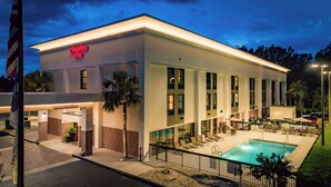 Un hôtel moderne doté d’une piscine, d’une enseigne « Bienvenue » et d’une enseigne « Hampton Inn ».