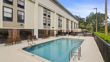Una piscina al aire libre, sillones reclinables de piscina