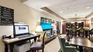 Une chambre d’hôtel équipée d’un bureau, d’un ordinateur, d’une imprimante et d’un téléviseur. Un panneau indique les numéros de chambre et les équipements disponibles.