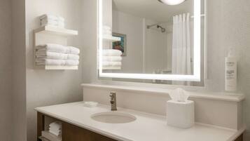 Un baño moderno con un lavamanos blanco, un espejo y un perchero para toallas.